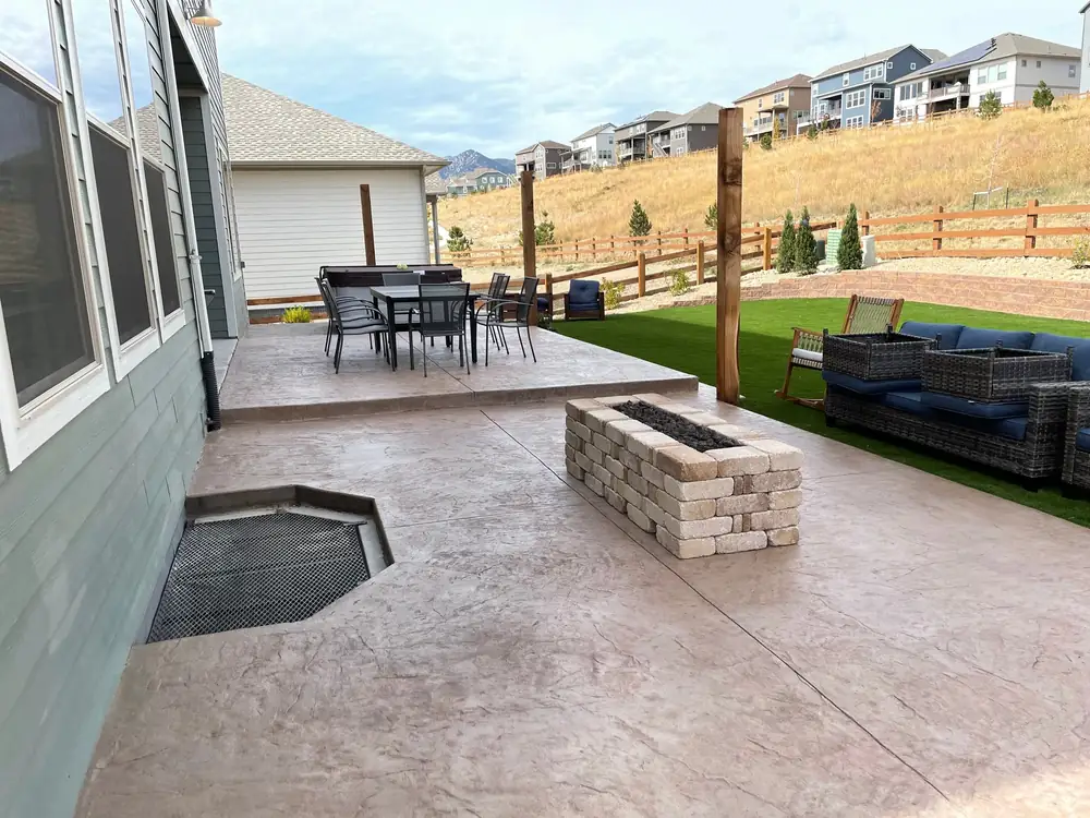 Stamped concrete patio with a block fire table, turf and a foothills view