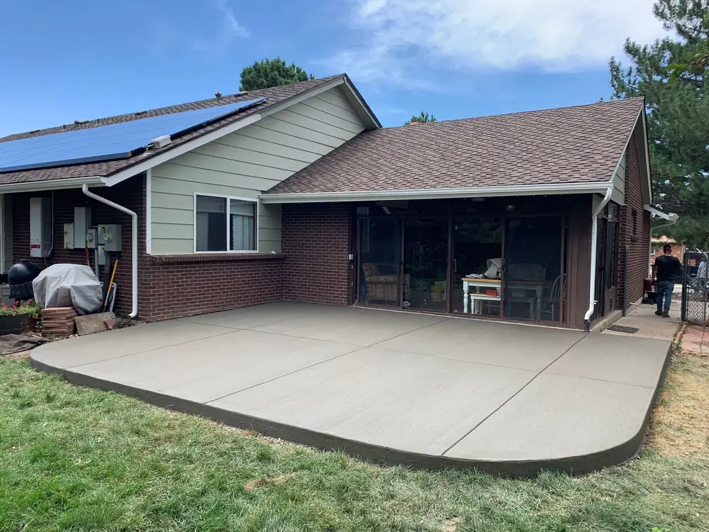 New concrete patio and lawn behind a brick ranch house