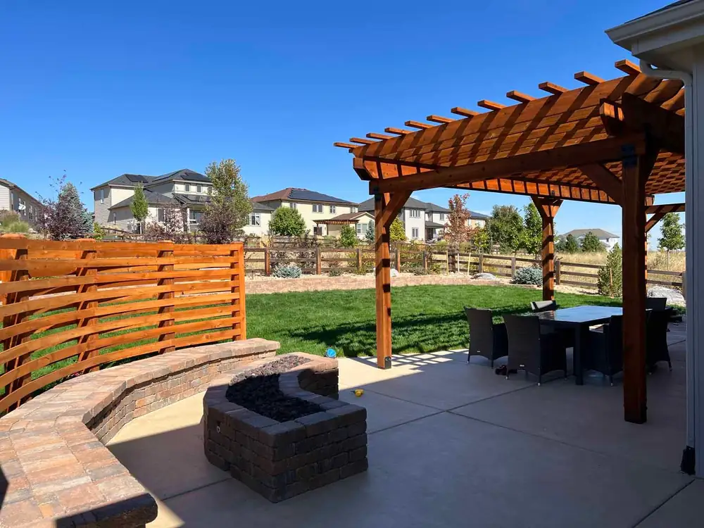 Wood pergola, curved paver seat wall and fire pit on a concrete patio