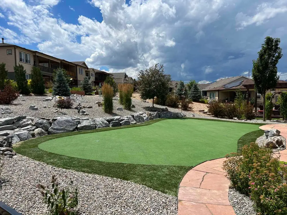 Artificial putting green with boulders, gravel beds and a flagstone path