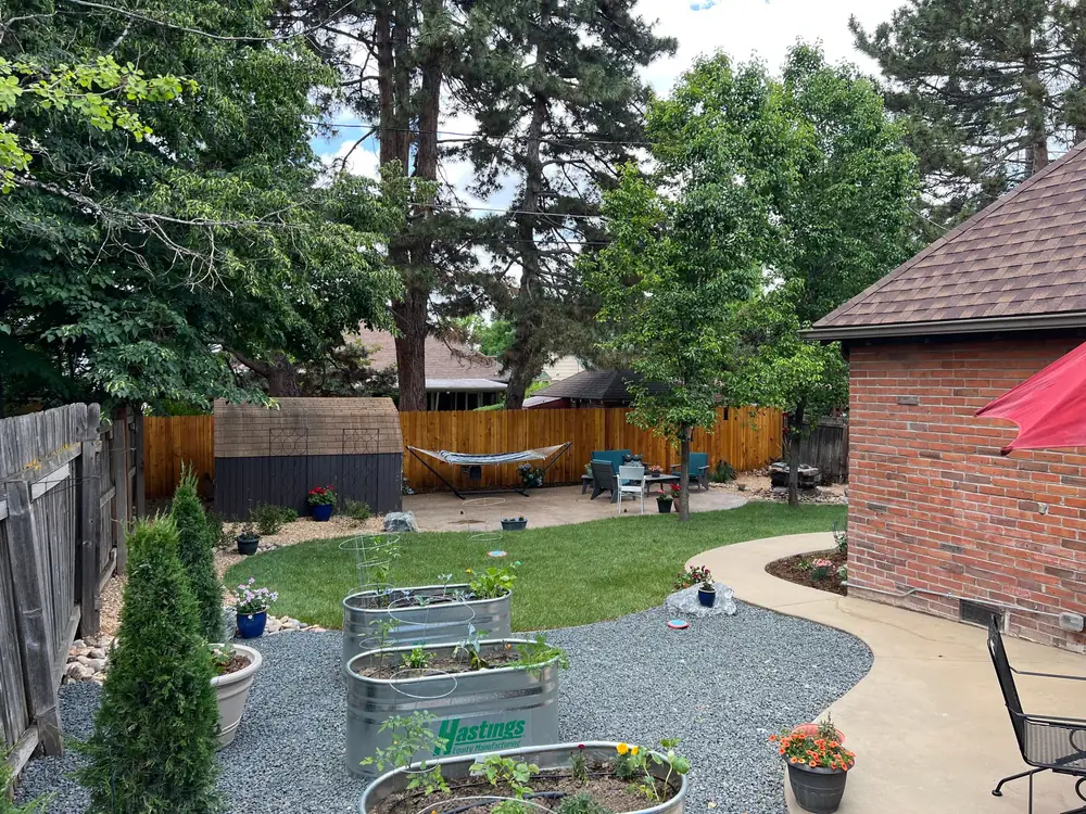 Galvanized raised garden beds on gravel paths beside a curved concrete walk