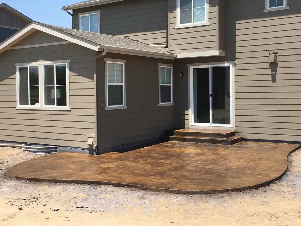 Stamped concrete patio off the back door of a two-story house