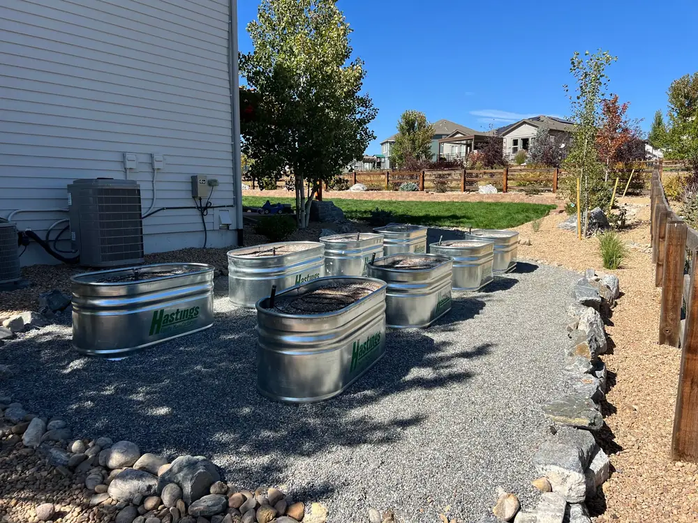 Stock tank planters on a gravel bed bordered with river rock