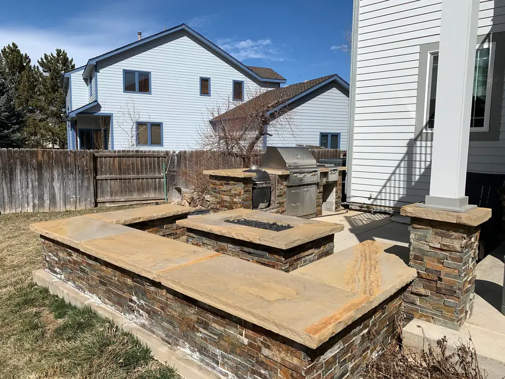 Stacked stone seat wall around a fire pit, next to a stone-faced grill island