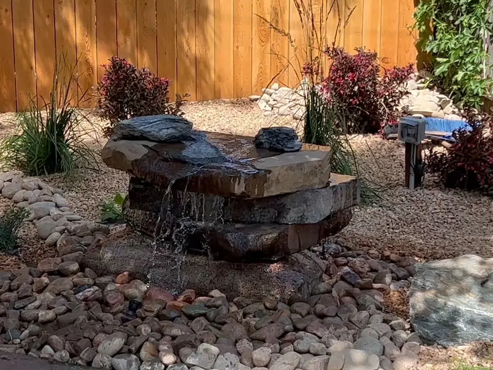 Stacked flagstone bubbling water feature in a rock bed